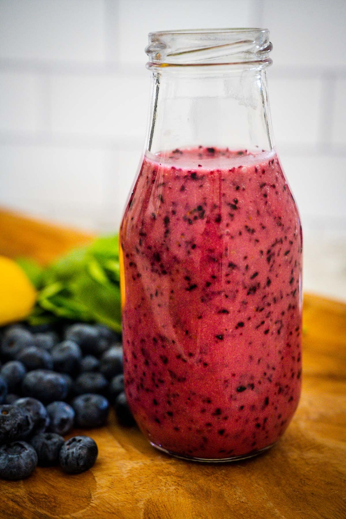 A clear bottle filled with fresh blueberry vinaigrette dressing.