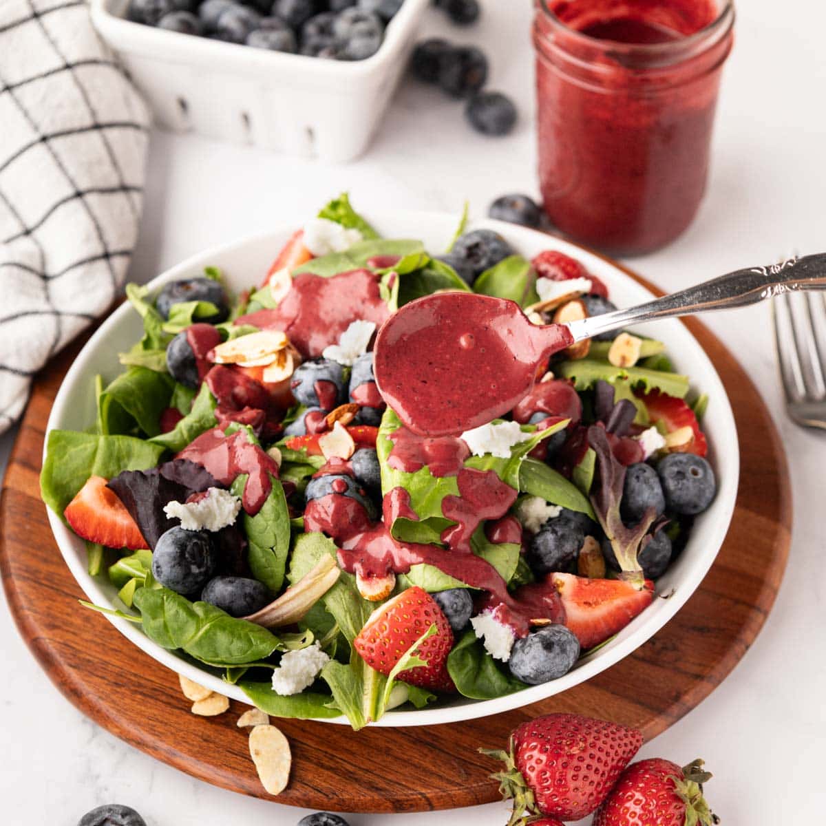 Spooning blueberry dressing on salad.