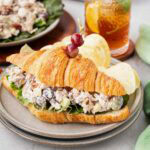 Chicken salad on a croissant on a plate with chips.