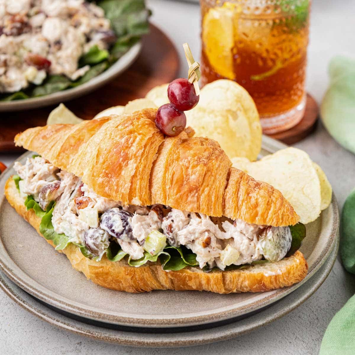 Chicken salad on a croissant on a plate with chips.