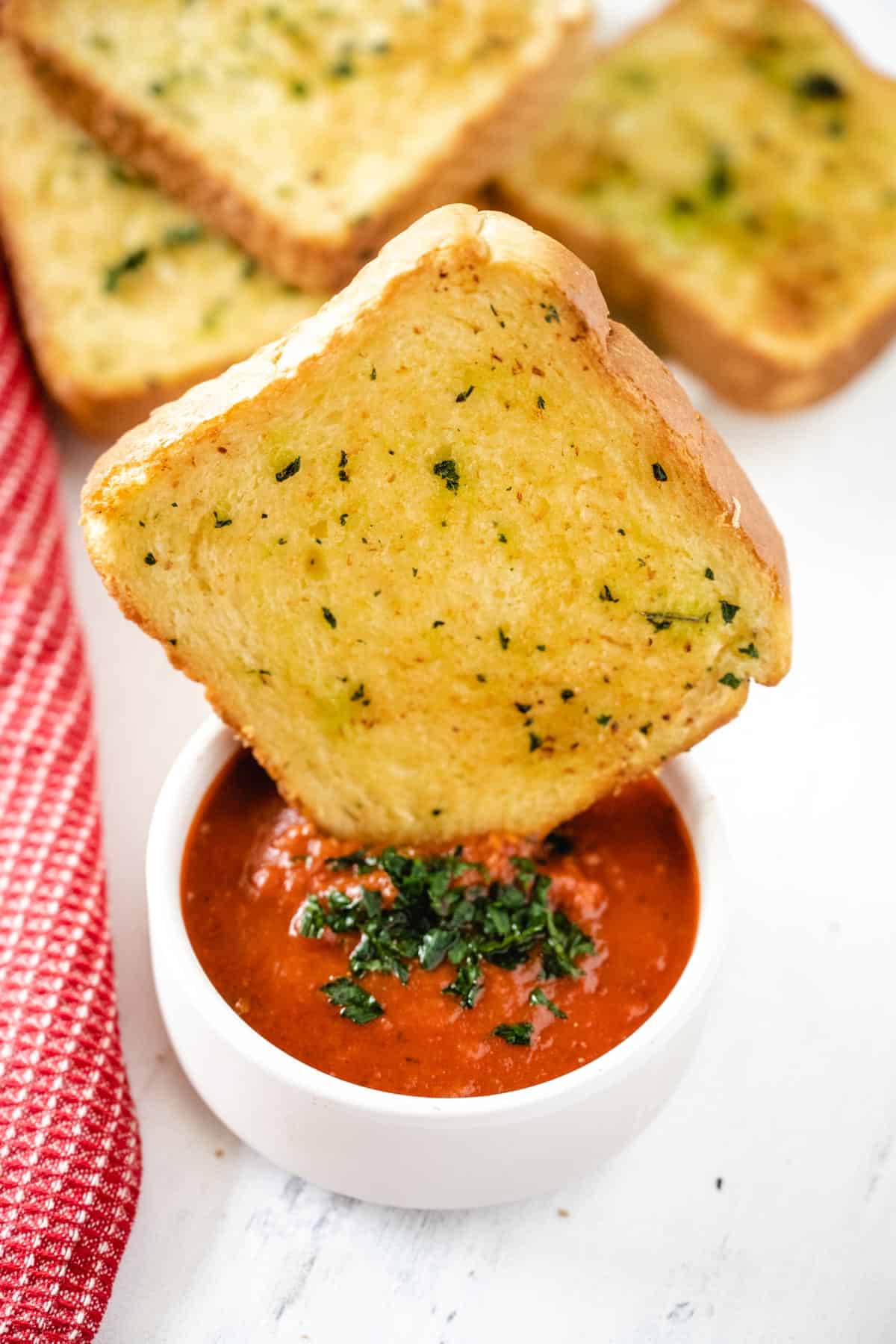 Air fryer Garlic Toast dipped into a marinara sauce topped with parsley.