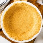 Upclose image of a homemade graham cracker crust in a white pie plate.