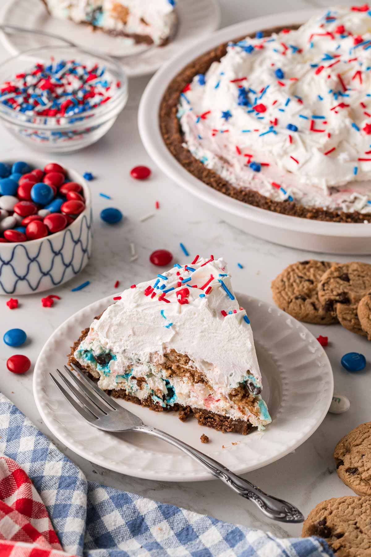 A slice of chocolate chip cookie cream pie on a plate with the pie in the background.