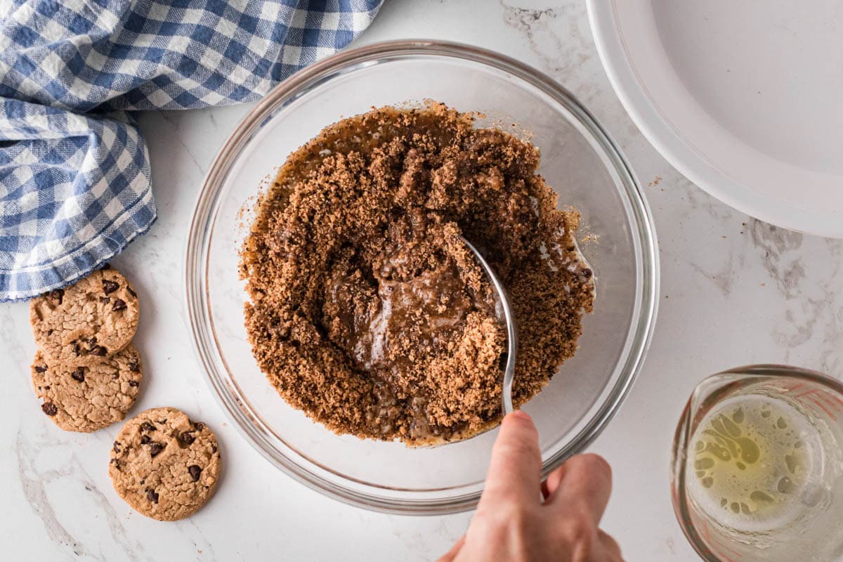 Cookie crumbs in a bowl being mixed with a fork to combine.