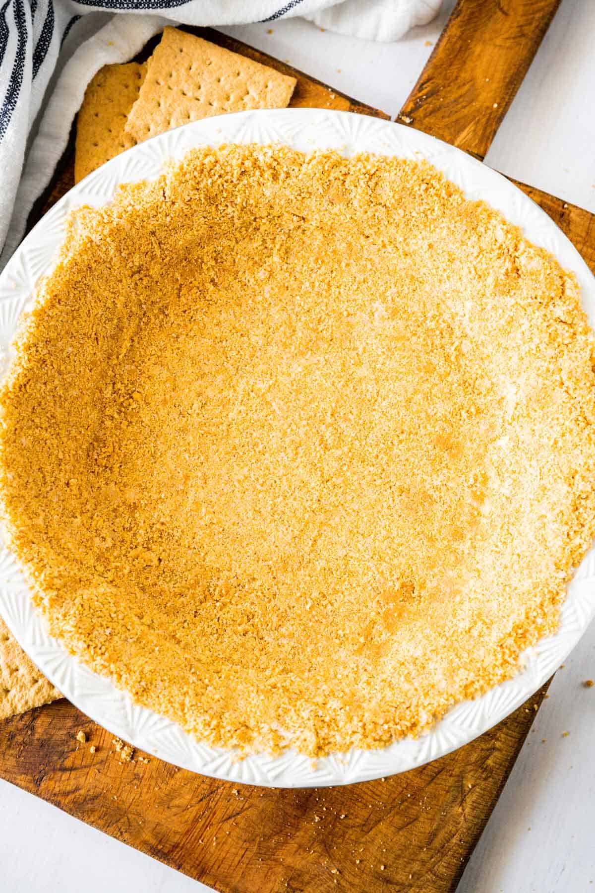 Overhead image of a no-bake homemade graham cracker crust on a wooden board.