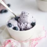 A bowl of no-churn blueberry ice cream spooned into a white bowl.