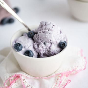 A bowl of no-churn blueberry ice cream spooned into a white bowl.