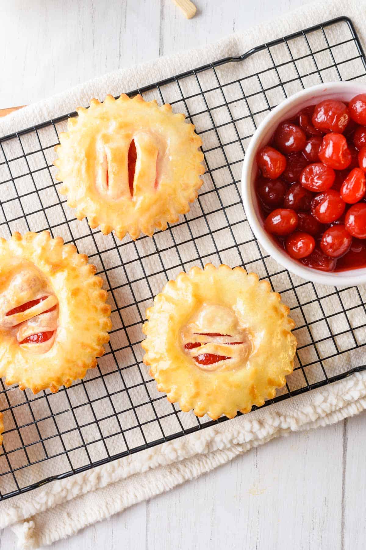 Three air fryer cherry hand pies cooling on a wire baking rack.