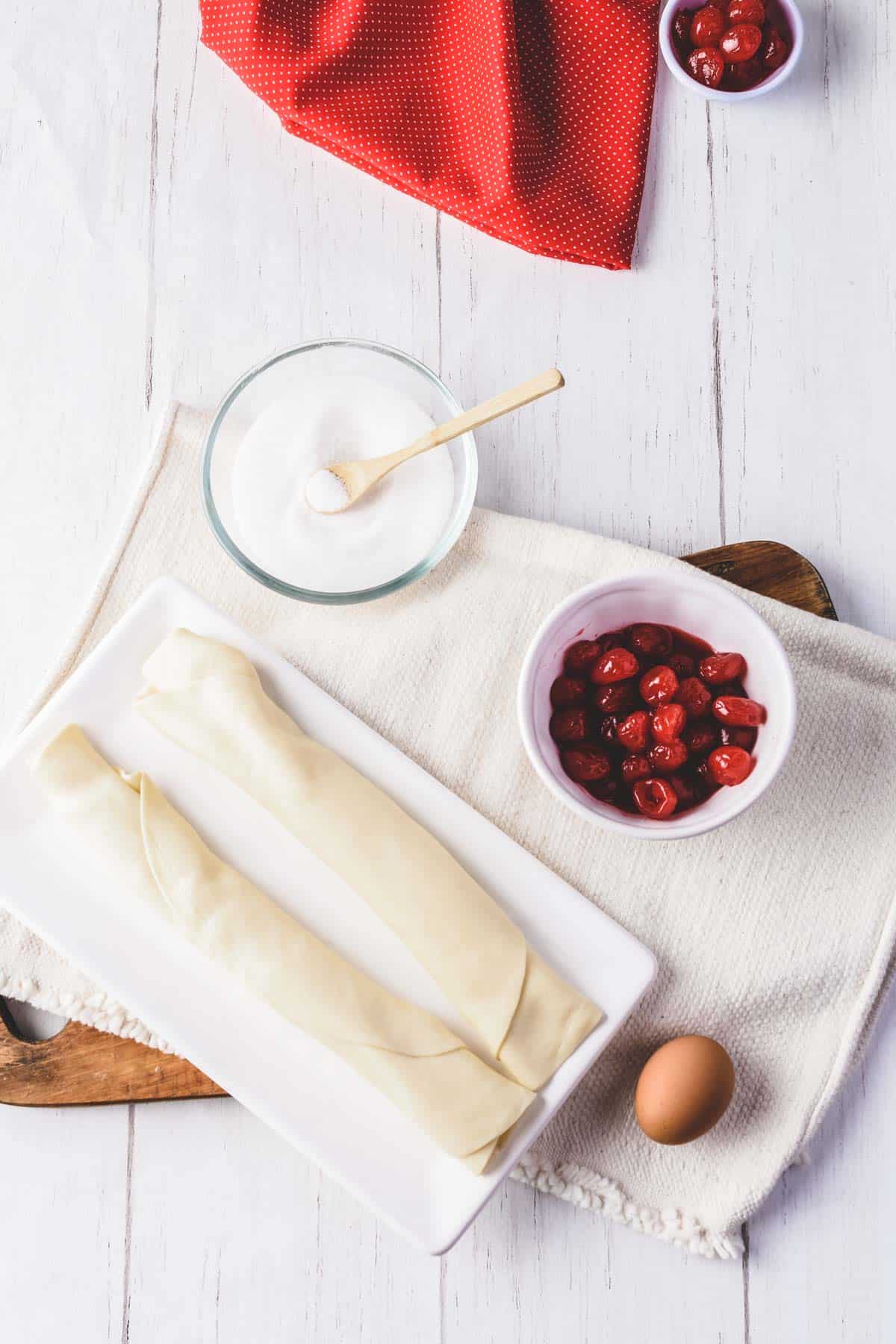 Ingredients needed for air fryer cherry hand pies - pie crust, cherry pie filling, egg, sugar and water.