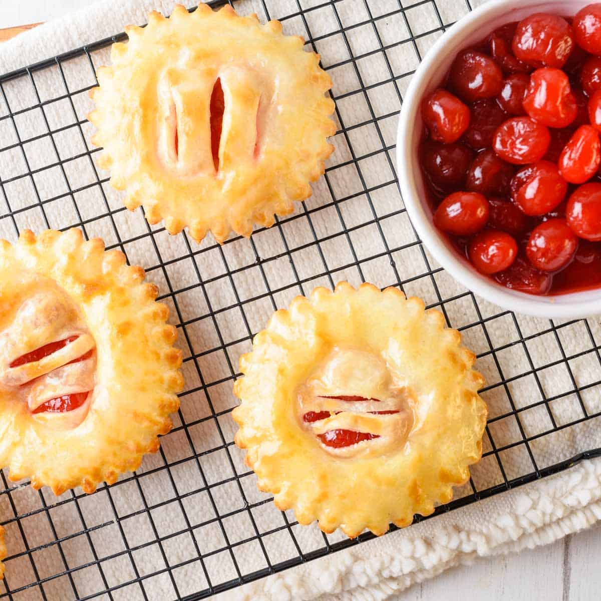 Air Fryer Hand pies on a wire cooling rack with a beige tea towel underneath.