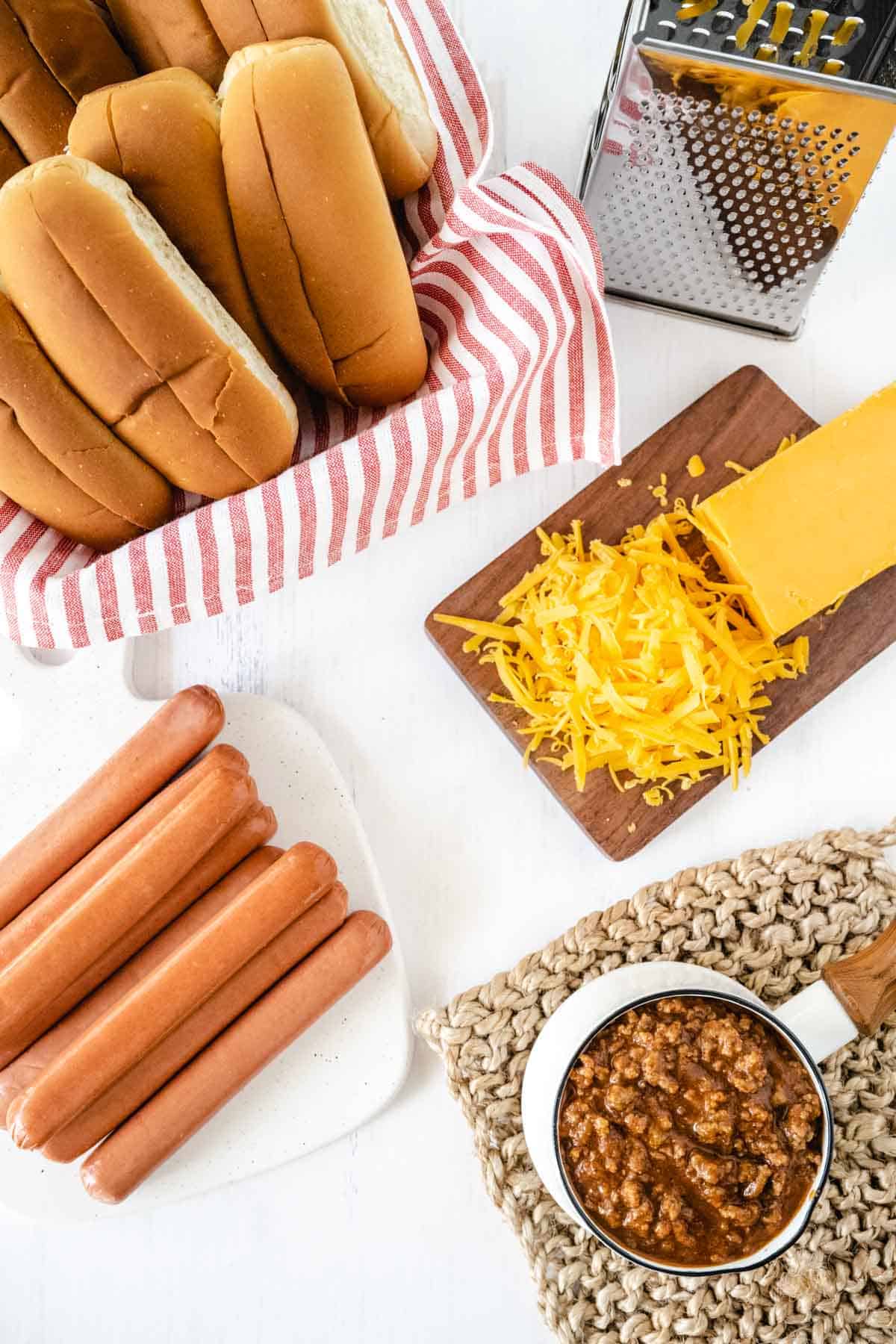 Baked Chili Cheese Dog Ingredients - hot dogs, hot dog buns, chili, and shredded cheddar cheese.