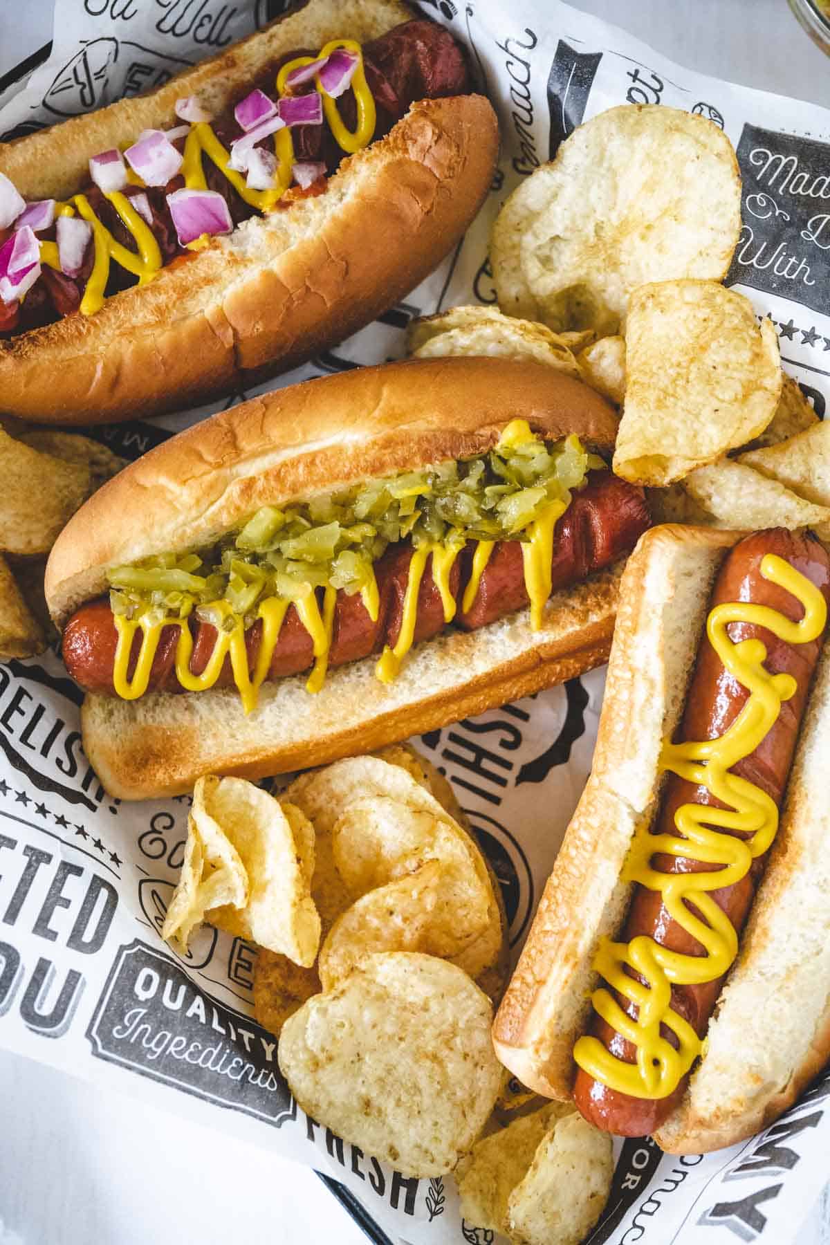 Air fryer hot dogs made three ways - one with mustard, one with mustard and relish, and one with ketchup, mustard and onions.