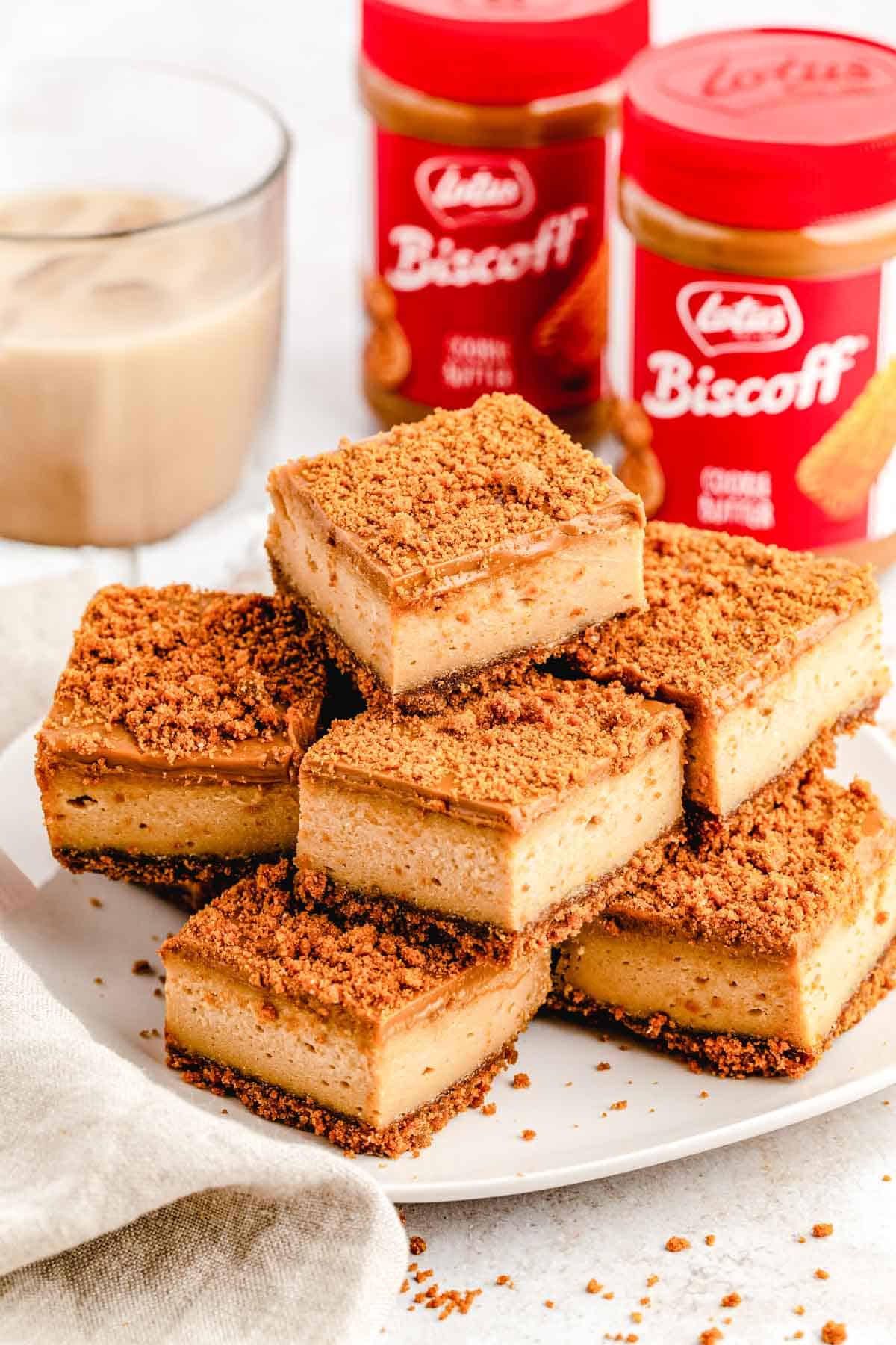Biscoff cookie butter cheesecake bars sliced and stacked on a white serving plate.
