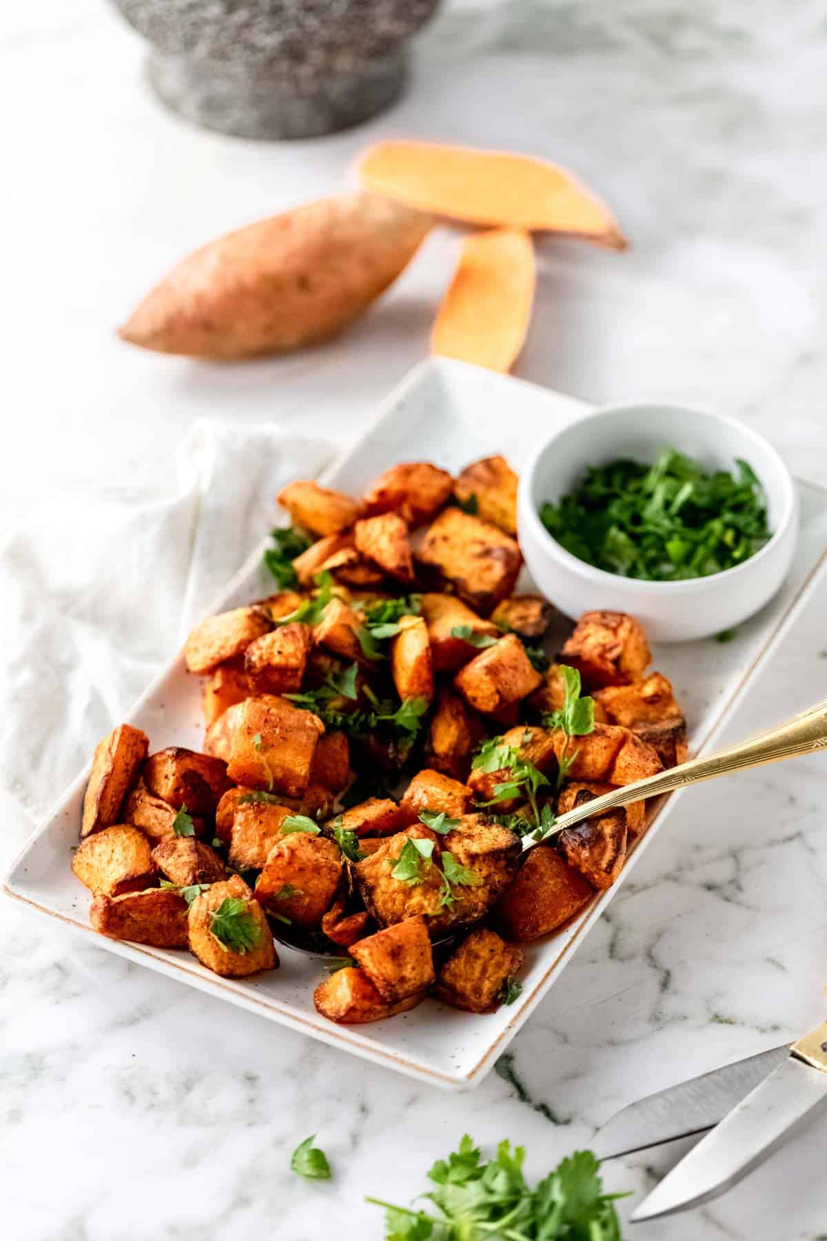 Air Fryer Sweet Potato Cubes on a white plate garnished with parsley.