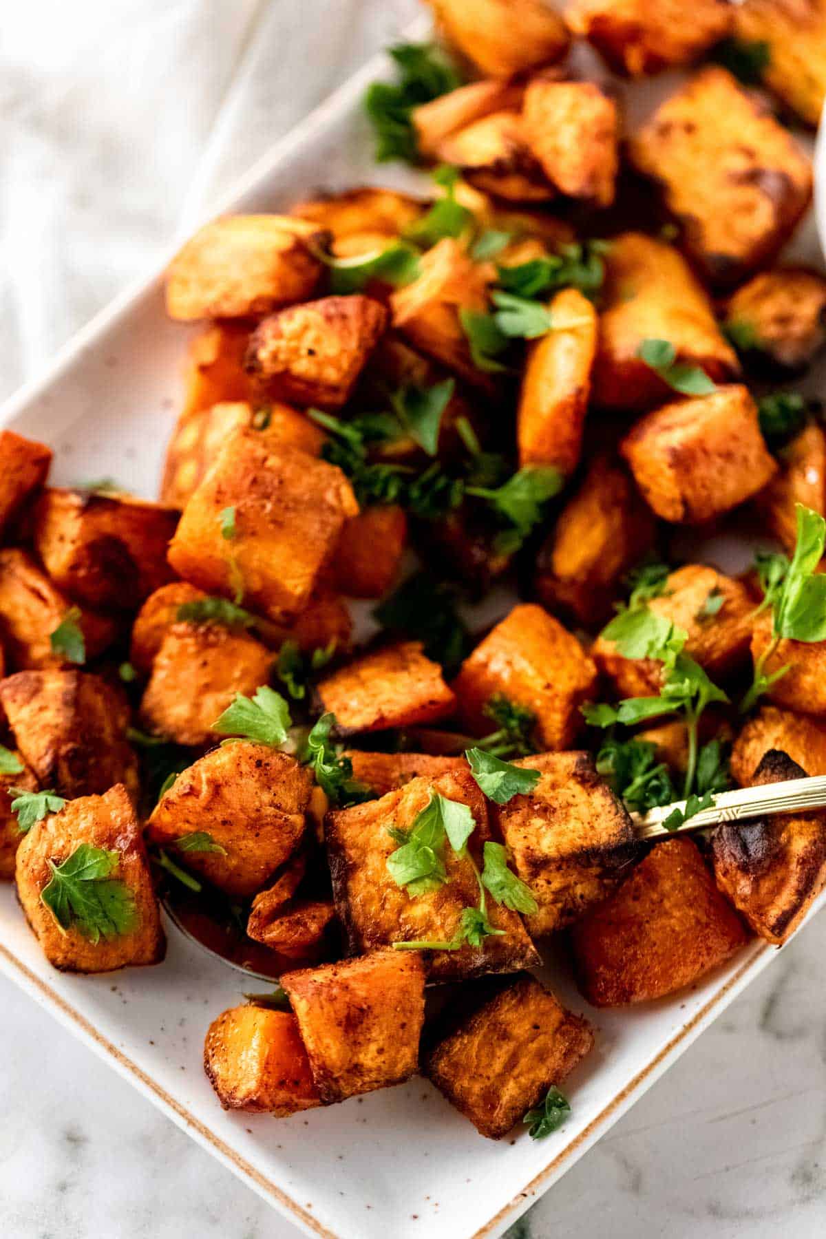 Upclose image of sweet potato cubes made in the air fryer being scooped with a spoon.