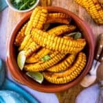 Overhead image of a bowl of air fryer corn ribs set on a wooden tray.