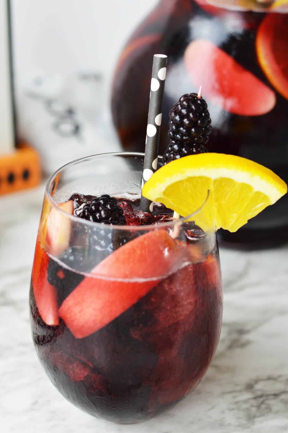 A glass of sangria with the pitcher in the background.