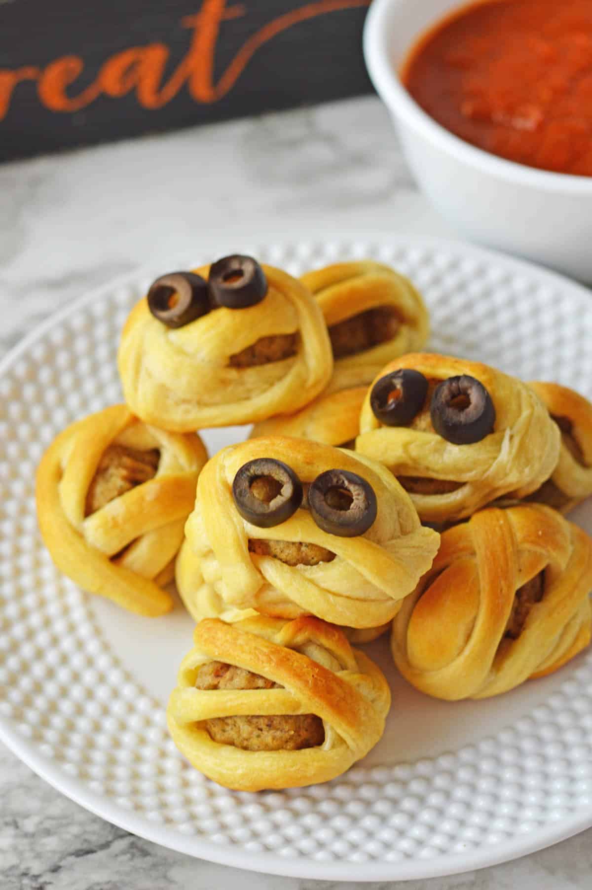 An up close image of a plate of meatball mummies.