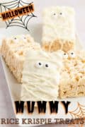 A plate of rice krispie treats decorated like mummies on a white plate with Halloween graphics on the image.