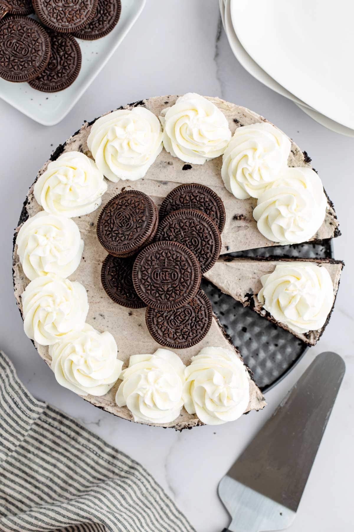 An overhead image of a whole no bake oreo cheesecake with a slice removed.