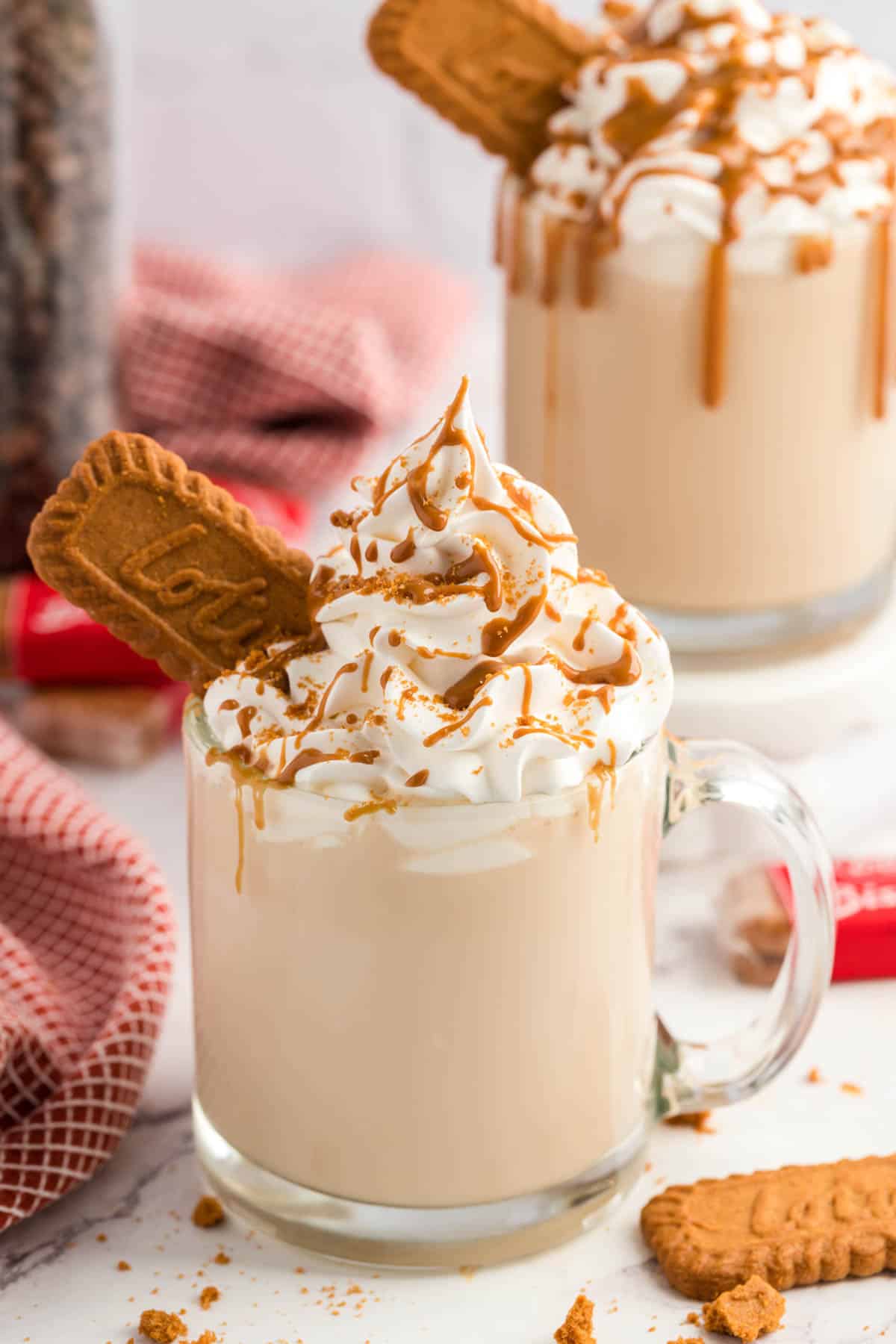 Two Biscoff Cookie Butter Latte topped with whipped cream, cookie butter crumbles and melted cookie butter.