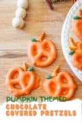 Pinterest image of chocolate covered orange pumpkin pretzels on a wooden tray.