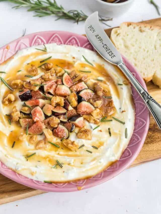 A wooden board with sliced artisan bread an a bowl filled with feta dip.