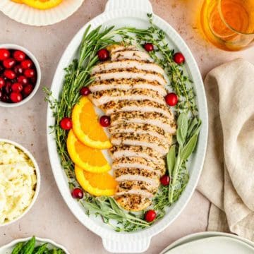 A tablescape filled with sliced turkey, asparagus, mashed potatoes, cranberries and wine.