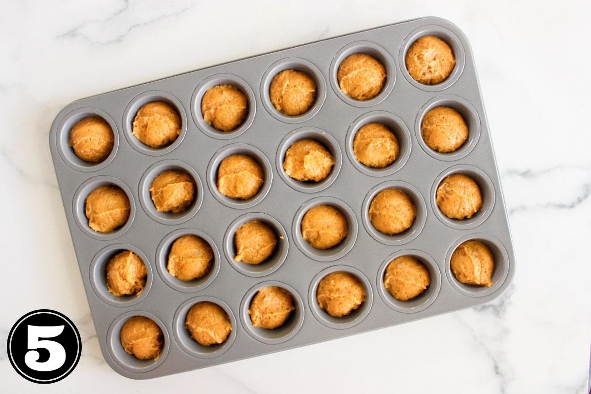 Pumpkin donut muffin batter in mini muffin pan.