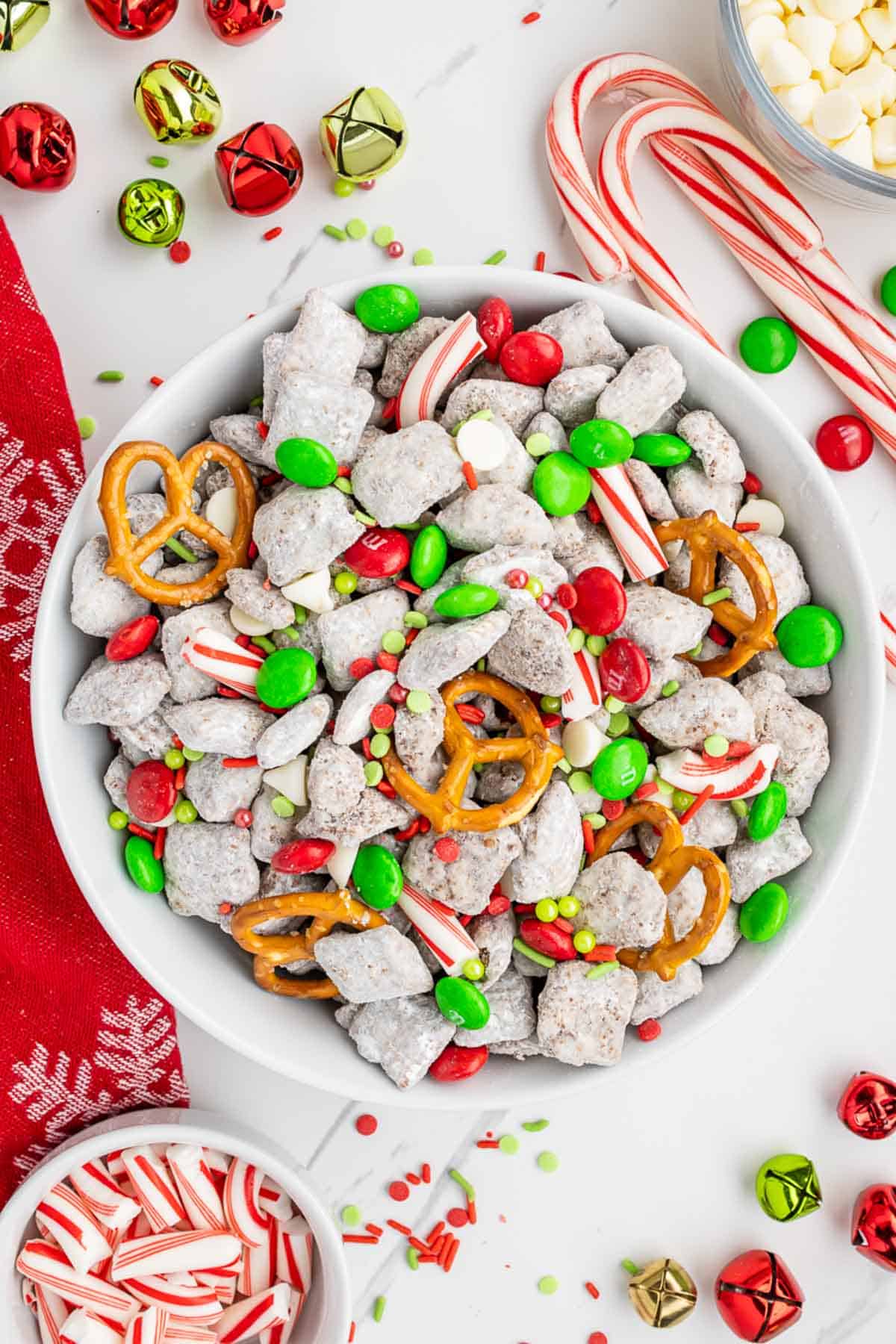 An overhead image of a festive tablescape serving Christmas Chex mix dessert in a white bowl.