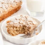 A slice of cinnamon toast crunch cake on a white plate with a bite removed and a fork set on the plate.