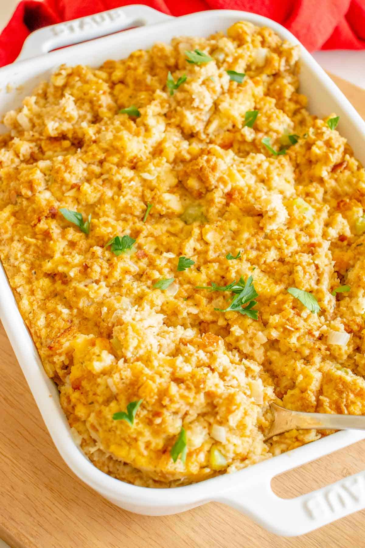 A pan full of a simple cornbread dressing garnished with parsley.