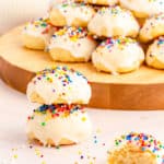 Two stacked Ricotta cookies stacked with a wooden tray of cookies in the background.