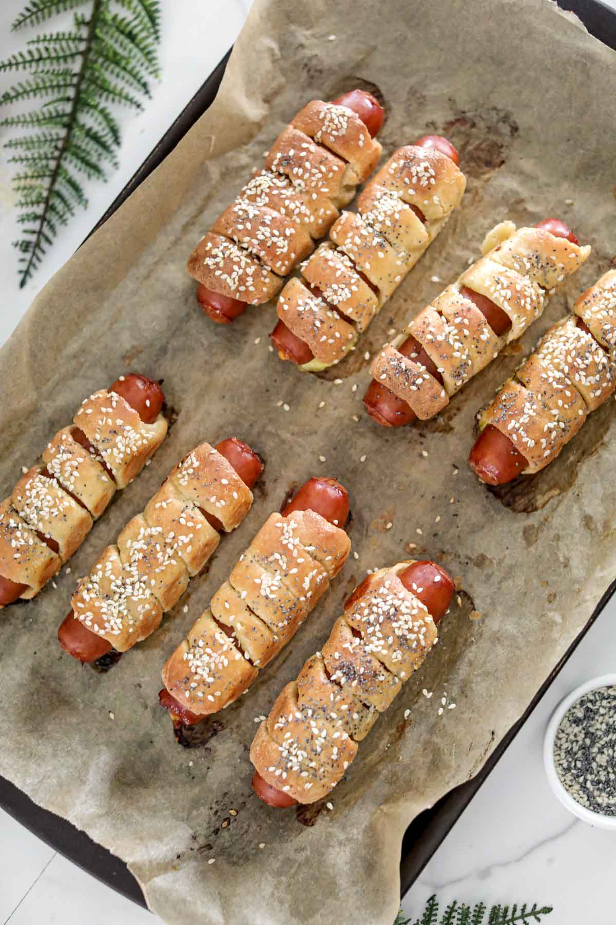 A tray of baked keto pretzel bagel dogs.