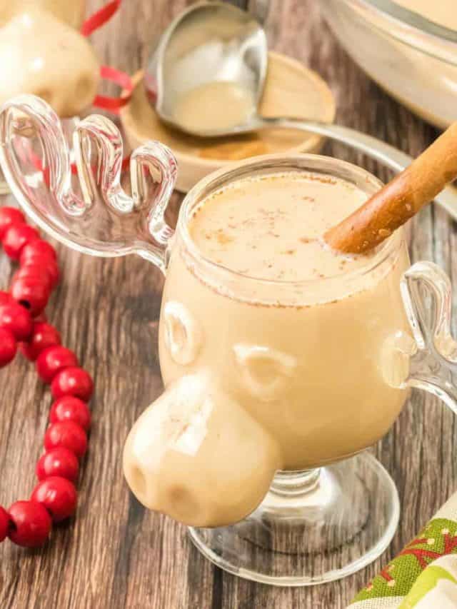 A cup of homemade eggnog in a moose cup garnished with a cinnamon stick.