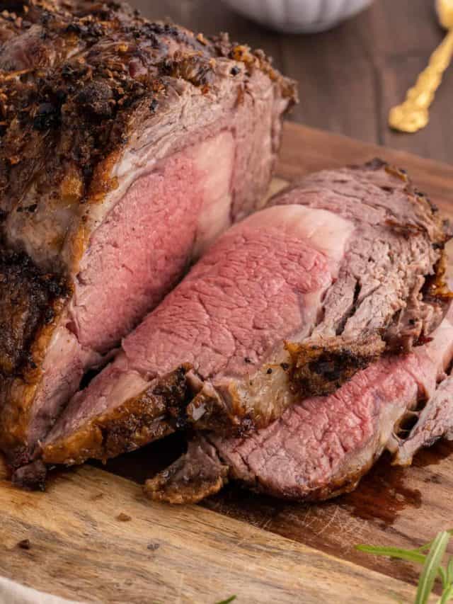 A sliced standing rib roast on a wood cutting board.