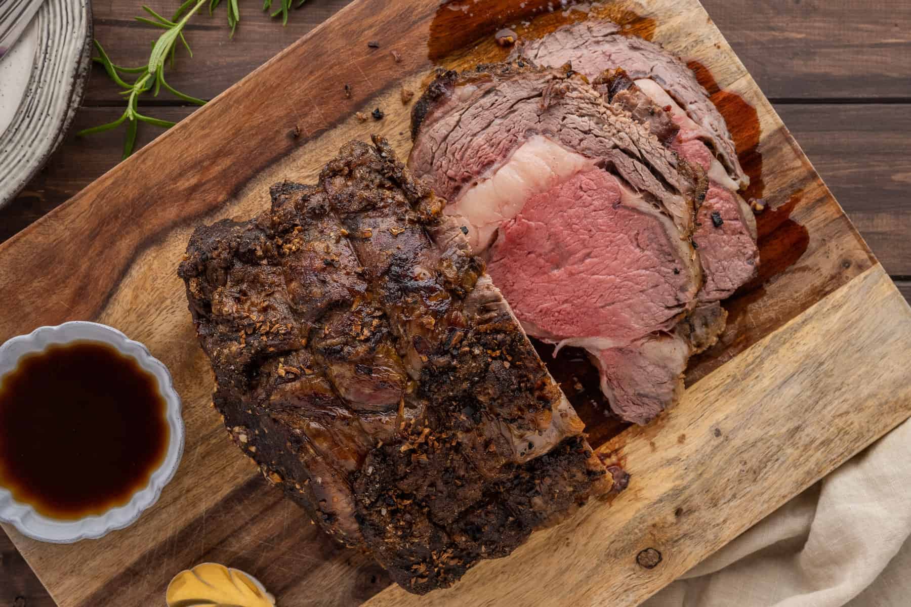 An overhead image of the prime rib half sliced on a cutting board.