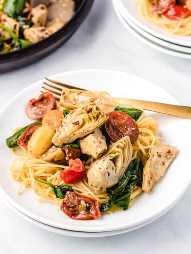 A plate of pasta with Italian artichoke hearts, cherry tomatoes, and spinach.