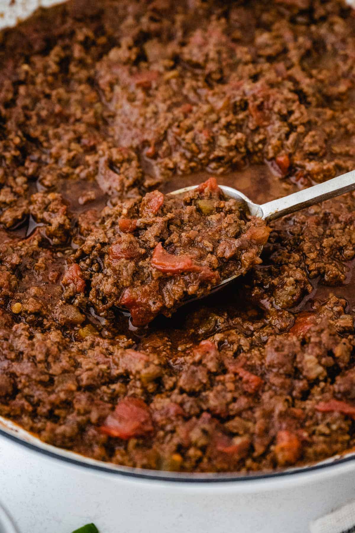 A pot of keto chili with no beans being scooped out with a silver serving spoon.