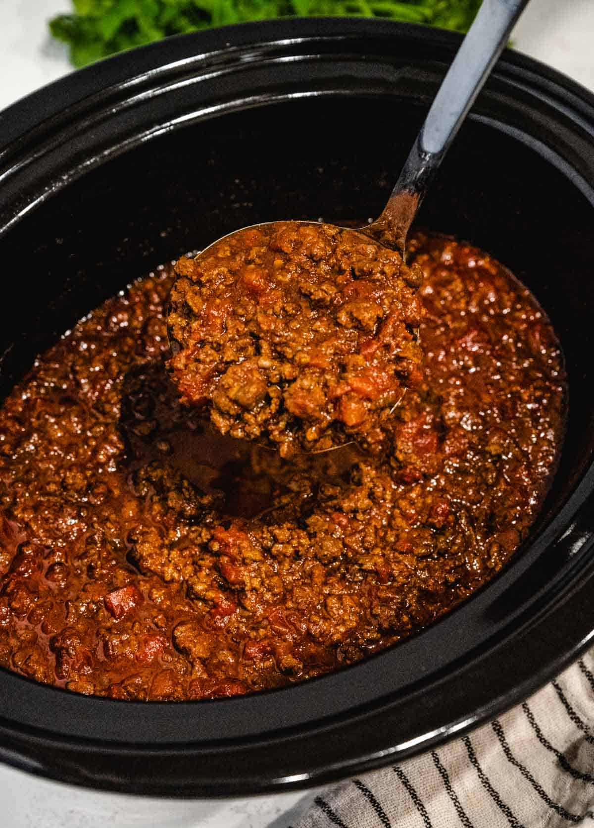 A crock pot filled with keto chili scooped out with a silver ladle.