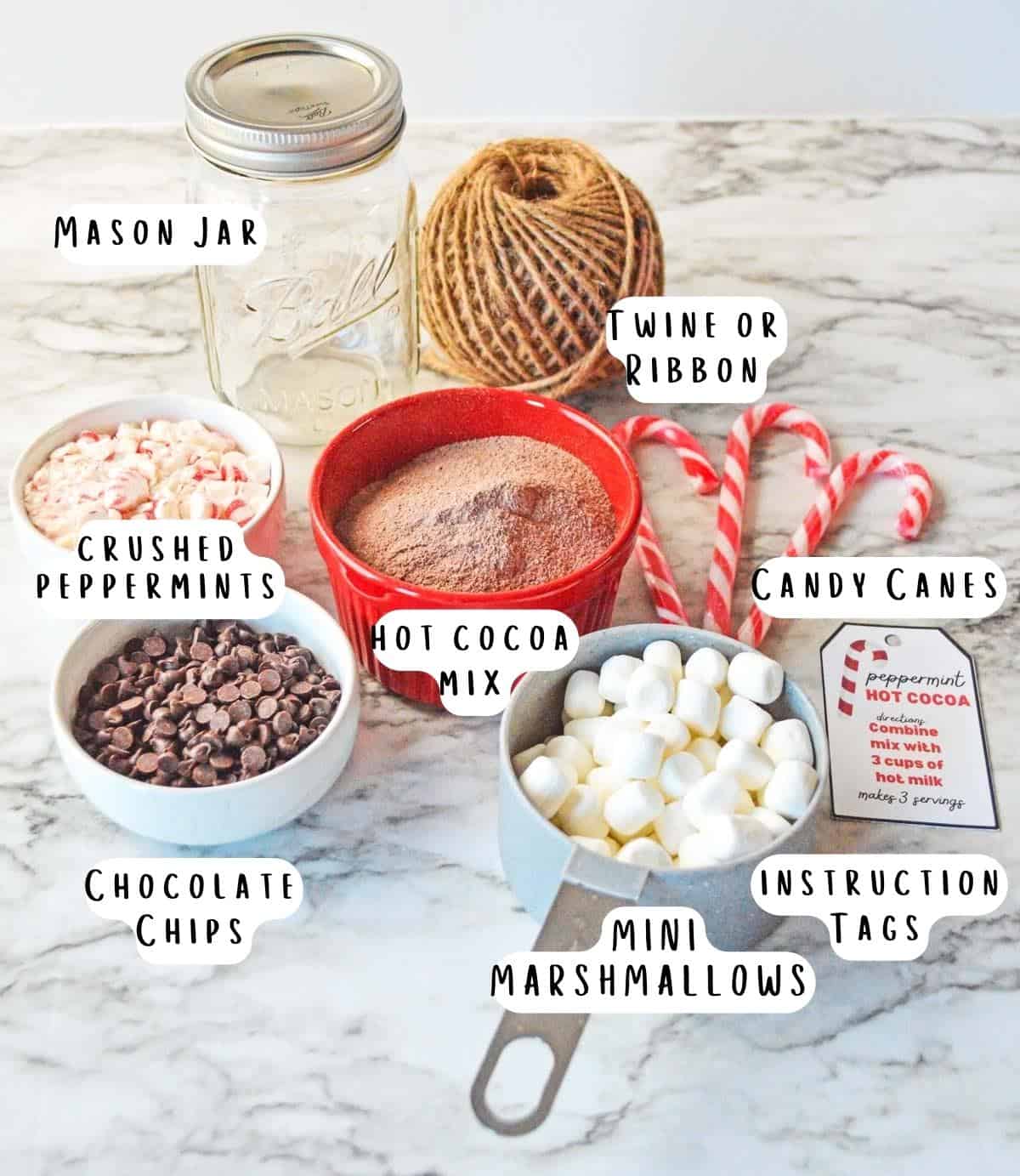 Labeled ingredients needed for peppermint hot cocoa mix in a jar.