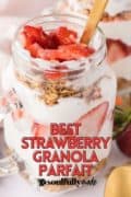 Best Strawberry Granola Parfait recipe image of a mason jar filled with the layers of yogurt, strawberries, and granola with a gold spoon.