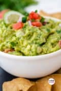 Pinterest image 4 showing homemade guacamole in a white bowl filled and garnished, and all surrounded by golden chips.