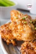 Pin 4 is an image only closeup of tan air fryer honey garlic chicken wing on a white plate.