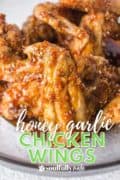 Honey Garlic Chicken Wings are on a white plate for this pin featuring the crsipy skin and homemade hoeny garlic sauce.