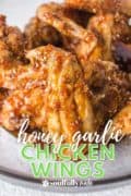Honey Garlic Chicken Wings are on a white plate for this pin featuring the crsipy skin and homemade hoeny garlic sauce.