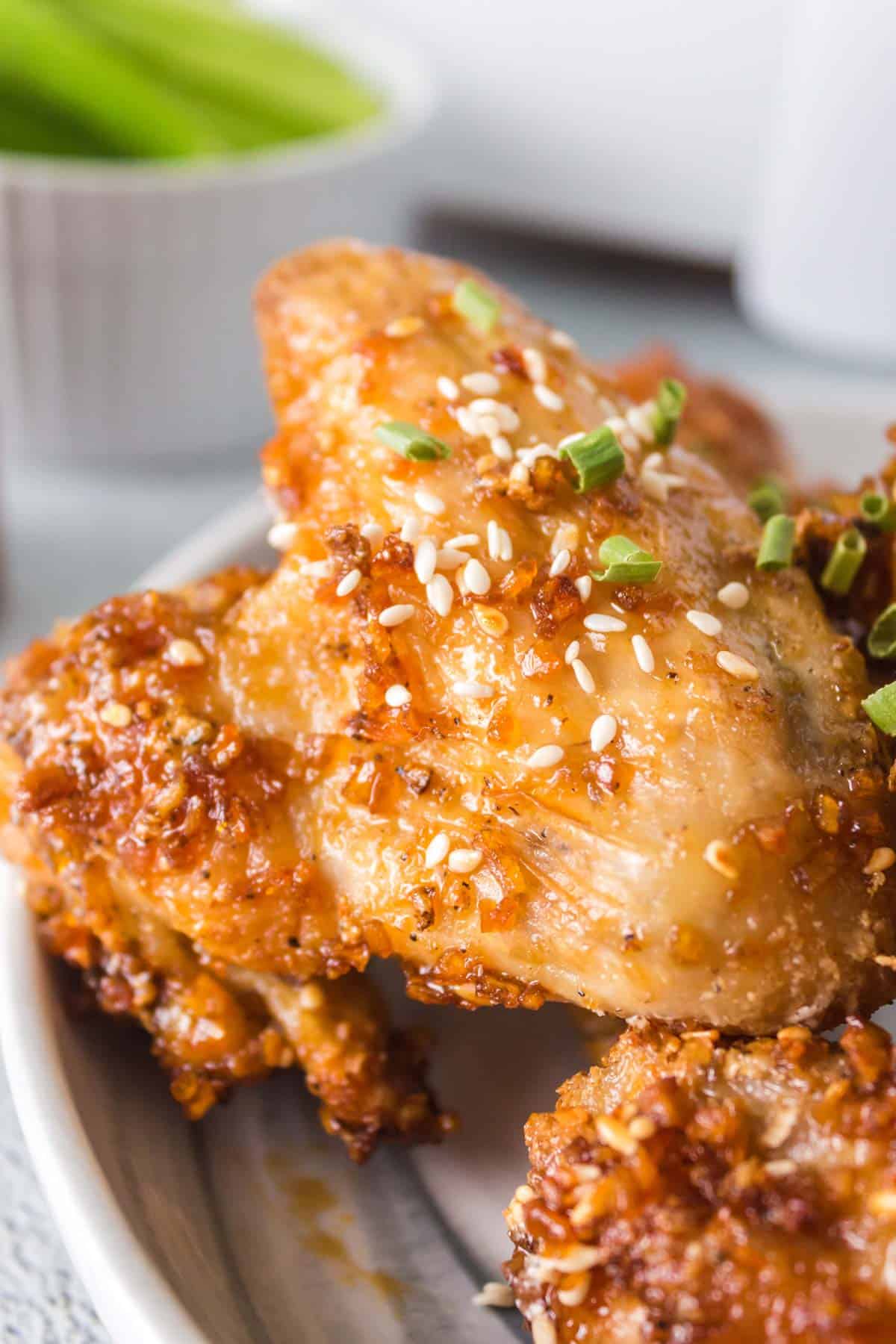 An upclose image of a gooey chicken wing coated with sesame seed garlic honey sauce.