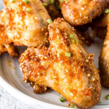 Gooey honey garlic chicken wings on a plate.