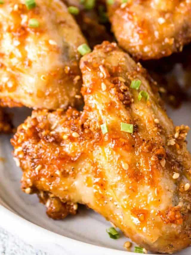 Gooey honey garlic chicken wings on a plate.