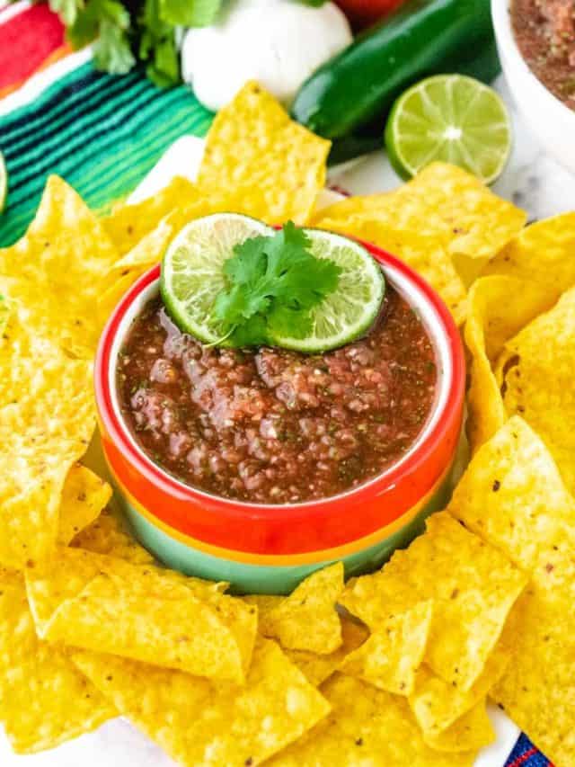 A bowl of restaurant style salsa surrounded by tortilla chips.